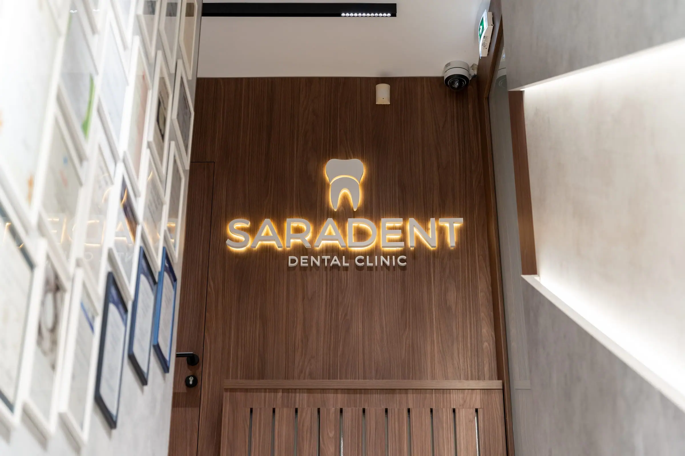 Hodnik s diplomama i osvijetljenim logotipom na zidu od oraha