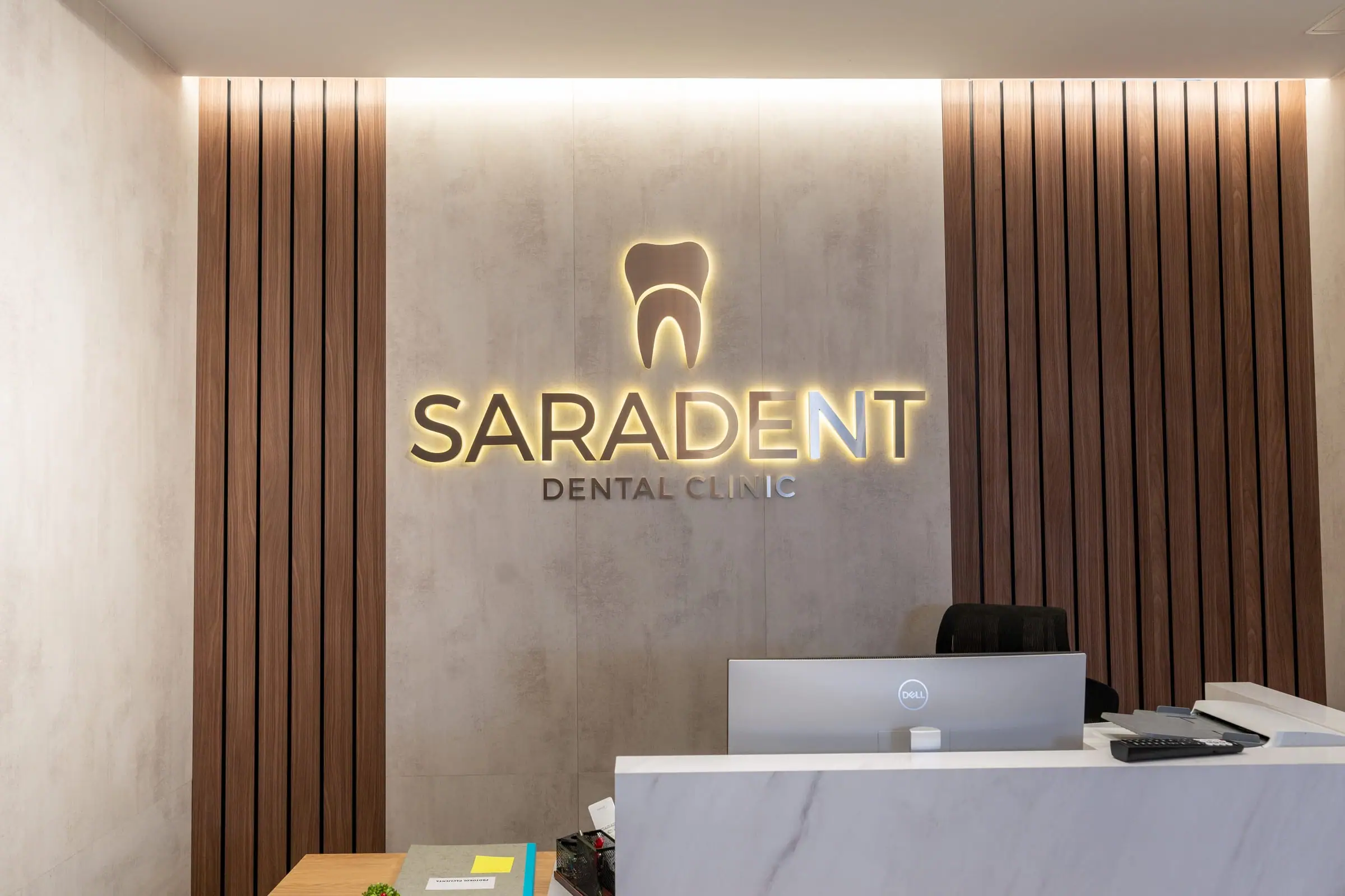 Mermerni recepcijski pult ispred zida sa zlatnim natpisom Saradent